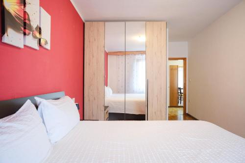 a bedroom with a white bed and a red wall at Residenza Garibaldi in Molveno