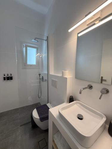 a white bathroom with a sink and a mirror at Green Dream in Tinos Town