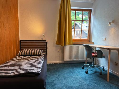 a bedroom with a bed and a desk and a window at Pension Thilo in Bad Wildbad