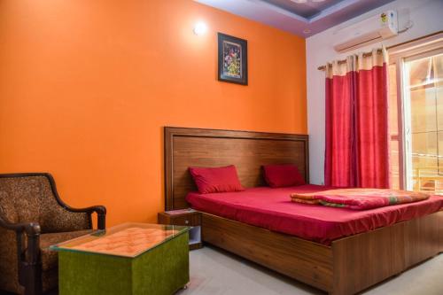 a bedroom with orange walls and a bed with red sheets at Upper Tapovan Resort in Rishīkesh