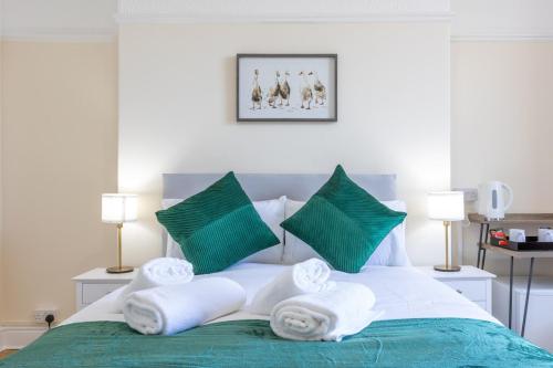 a bedroom with a bed with green and white pillows at Entire Home on Beach Front, Sleeps 25 with Free Parking in Rhyl