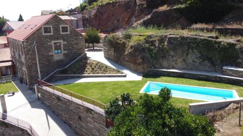 a house with a swimming pool next to a stone wall at Casa do Cruzeiro in Alvações do Corgo