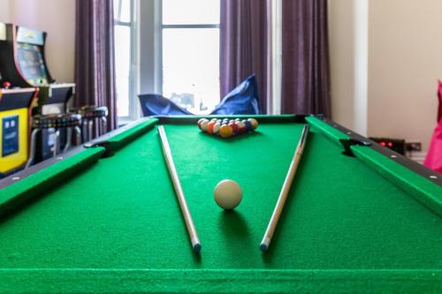 a pool table with three cue sticks and a ball at Entire Home on Beach Front, Sleeps 25 with Free Parking in Rhyl