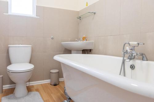a bathroom with a tub and a toilet and a sink at Entire Home on Beach Front, Sleeps 25 with Free Parking in Rhyl