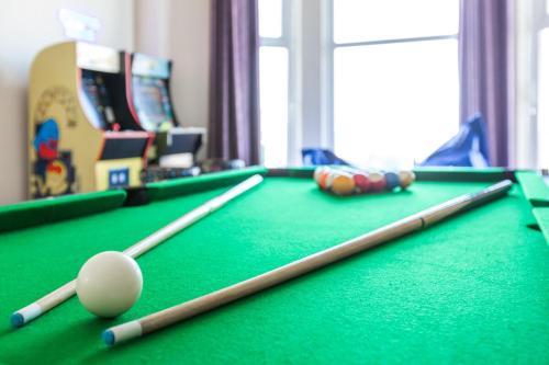 a pool table with two cue sticks and a ball at Entire Home on Beach Front, Sleeps 25 with Free Parking in Rhyl