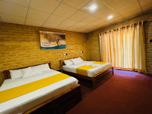 a bedroom with two beds and a brick wall at Elephant Arcade in Tissamaharama