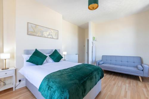 a bedroom with a large bed and a blue couch at Entire Home on Beach Front, Sleeps 25 with Free Parking in Rhyl