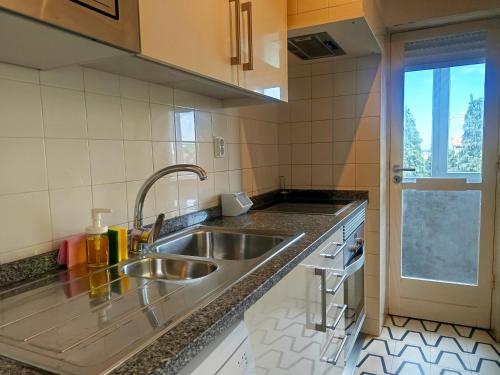 a kitchen with a stainless steel sink and a window at Combatentes Apartment in Porto
