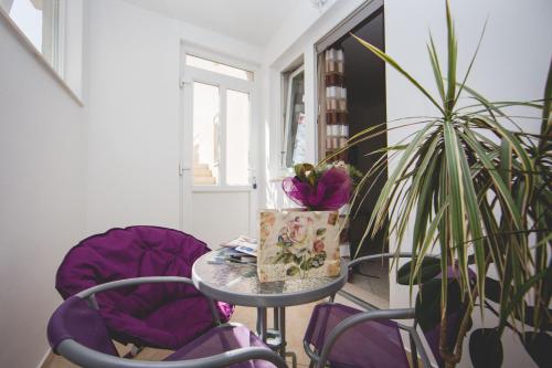 a table with purple chairs and a potted plant at Apartment Karla&Nella in Stobreč