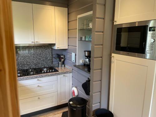a small kitchen with white cabinets and a microwave at Vrijstaande luxe Finse blokhut 2-6 pers in Kropswolde
