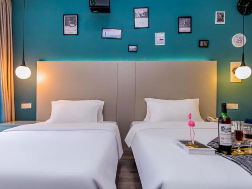 two beds in a room with a blue wall at 重庆莎霏酒店大渡口店 in Chongqing