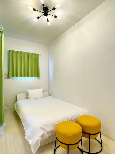 a bedroom with a bed and two yellow stools at The Marina Bay in Fukuoka