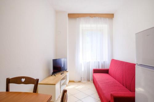a living room with a red couch and a tv at Residenza Garibaldi in Molveno