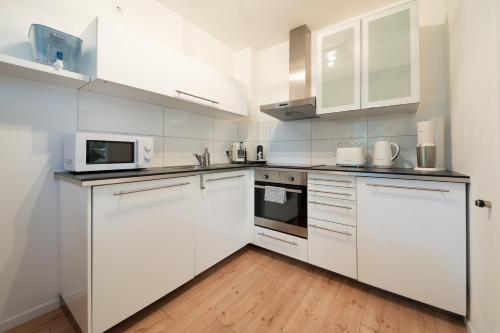 a white kitchen with white cabinets and white appliances at Central Studio Near Main Train Station & Old City Hall in Wuppertal