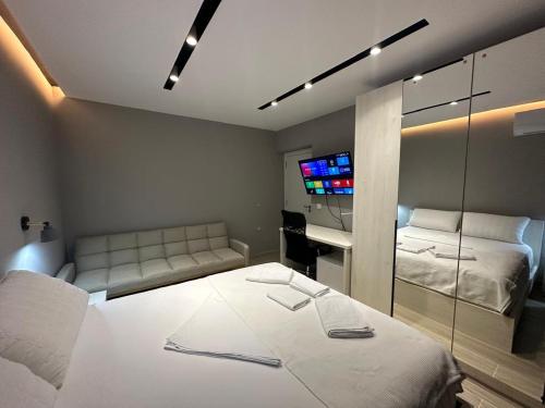 a room with two beds and a couch and a tv at Ionian rooms in Vlorë