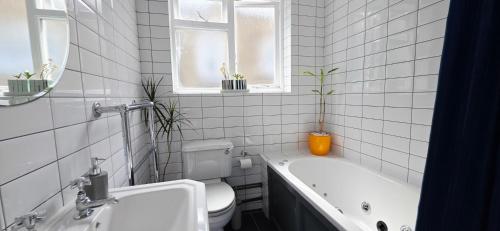 a bathroom with a tub and a toilet and a sink at Double Bed at Cozy Hailsham in London