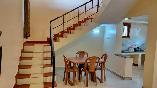 a dining room with a table and chairs and stairs at Pears Tree Duplex Villa in Kodaikānāl