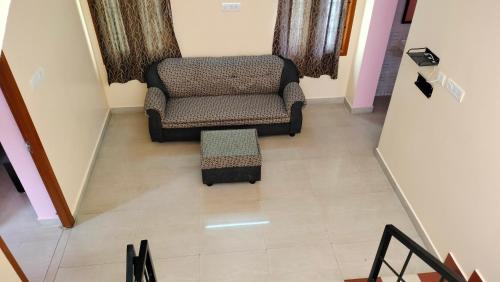 a living room with a chair and a stool at Pears Tree Duplex Villa in Kodaikānāl