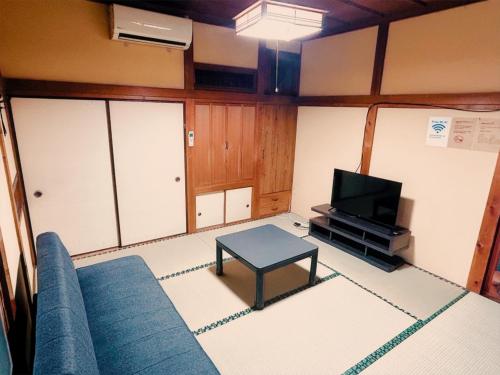 a living room with a blue couch and a tv at 質本宿Shichibonya戸尾町 in Sasebo