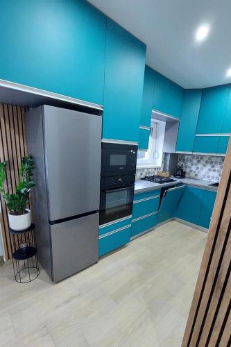 a kitchen with blue cabinets and a stainless steel refrigerator at Kilian Suite in Miskolc