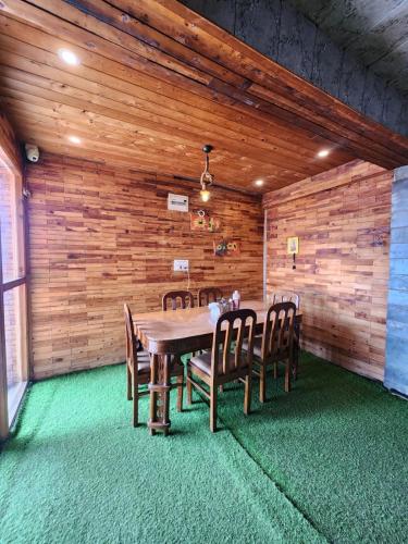a wooden dining room with a table and chairs at Sneh by Daisey in Cheog