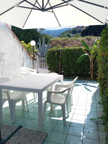 a white table and chairs with an umbrella on a patio at Casa sul mare vicino Diamante in Belvedere Marittimo