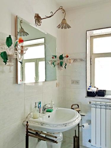 a white bathroom with a sink and a mirror at Vista Alcantara - Wellness Mountain-Top Retreat in Motta Camastra
