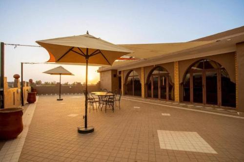 a patio with a table and an umbrella at Villa Alnatura with heated pool overlooking the High Atlas in Tillouna