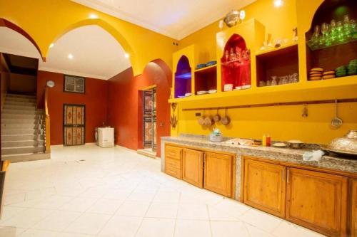 a large kitchen with orange and yellow walls at Villa Alnatura with heated pool overlooking the High Atlas in Tillouna
