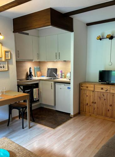 a kitchen with white cabinets and a table with a laptop at Cozy appartement style chalet in Torgon