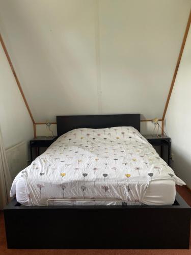 a bed with a white comforter on top of it at Vrijstaande luxe Finse blokhut 2-6 pers in Kropswolde