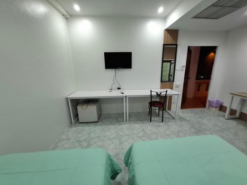 a room with two beds and a desk with a tv at โรงแรมฟร้อนบีช frontbeach in Ban Pak Nam Pran