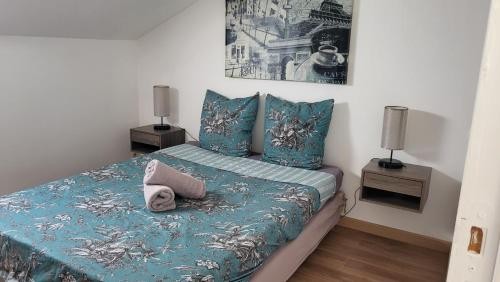 a bedroom with a bed with blue sheets and two lamps at les chambres de Mélis in Crémieu