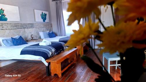 two beds in a bedroom with yellow flowers in the foreground at Von Loë Huizen in Fauresmith