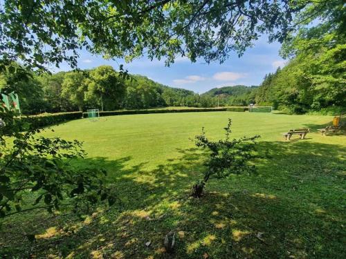 a park with a bench and a large green field at De Oranje Kabouter in Durbuy
