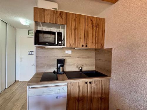 une petite cuisine avec un évier et un micro-ondes dans l'établissement Appartement 2 pièces-mezzanine pour 6 pers. avec balcon sud/ouest, skis aux pieds - Huez - FR-1-405-163, à Huez