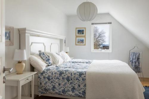 a white bedroom with a bed and a window at Poolvilla på Österlen in Brantevik