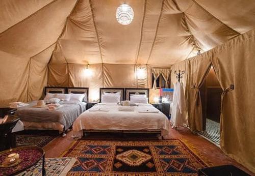 a bedroom with two beds in a tent at Host Luxury Camp in Merzouga