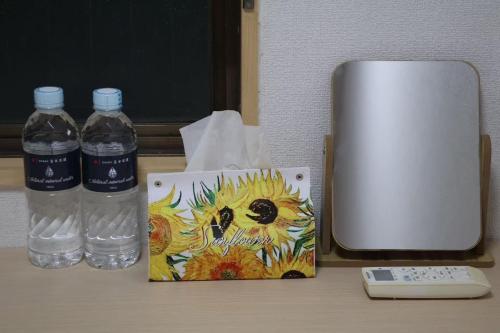 a desk with two bottles of water and a phone at ひまわりHotel in Nagasaki