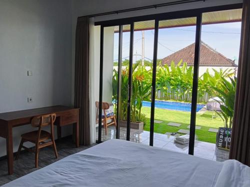 une chambre avec un lit, un bureau et une fenêtre dans l'établissement Kayla Homestay, à Nusa Dua