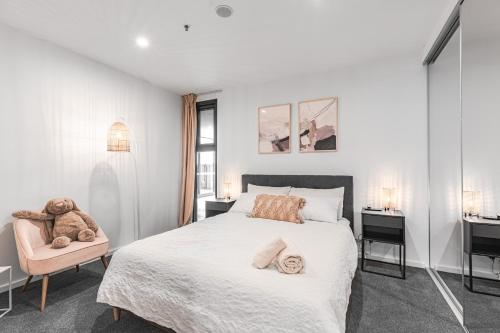 a bedroom with a large white bed and a chair at Rooftop patio w Mt View, Parking, Wifi n Netflix in Braddon