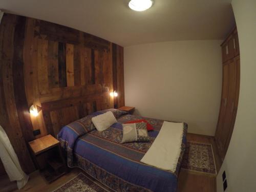 a bedroom with a bed with a wooden wall at Appartamento Pré-Saint-Didier, terme in Pré-Saint-Didier