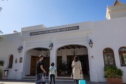 a family walking outside of a building with luggage at Villa Turística de Laujar de Andarax in Laujar de Andarax