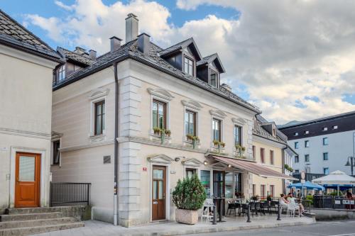 a white building on a street with tables and chairs at Apartmaji Gašperčič, NEJC in Bovec