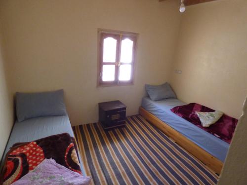 two beds in a room with a window at gîte taghia ahansal in Taghia