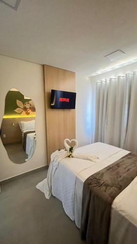 a hotel room with two beds and a clock on the wall at Flat Brisa do Mar - Centro Porto - 300 metros das piscinas naturais in Porto De Galinhas