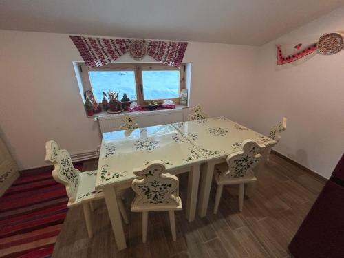 ein Esszimmer mit Tisch und Stühlen und einem Fenster in der Unterkunft Poiana cu Sinziene in Neagra Şarului