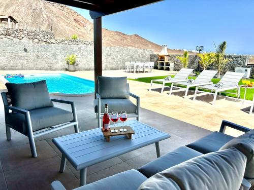 Un patio con un sofá y sillas y una mesa con copas de vino. en Villa Ocean Lanzarote, en Playa Blanca