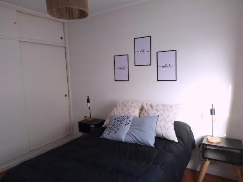 a bedroom with a bed and some pictures on the wall at San Benito Apart in Tandil