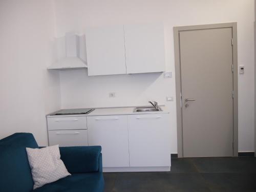 a kitchen with white cabinets and a blue couch at Hotel Vienna in Pesaro